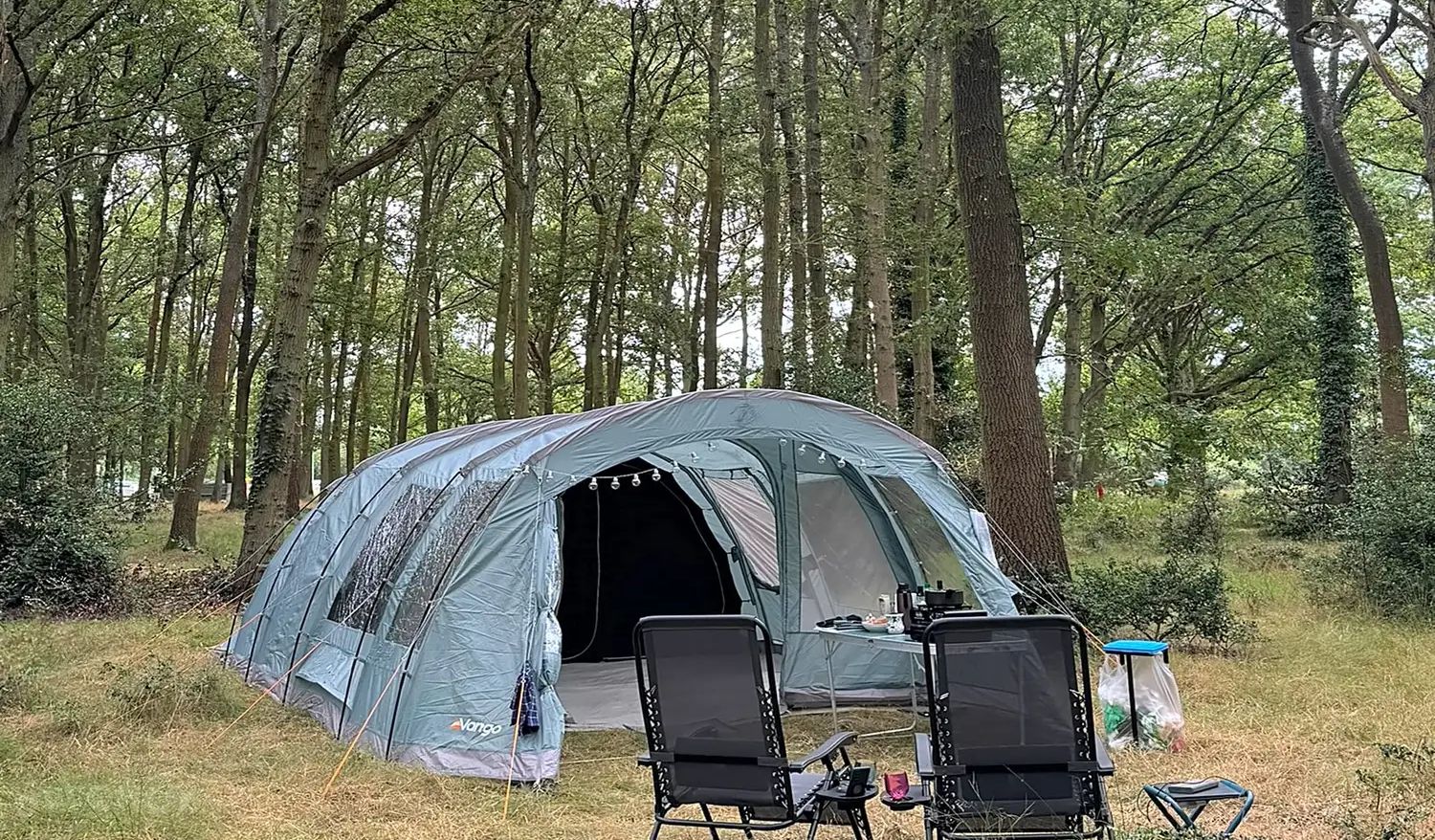 Camping chairs set out beside a tent in the sun